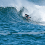 A man wearing a wetsuit riding a wave on a body board